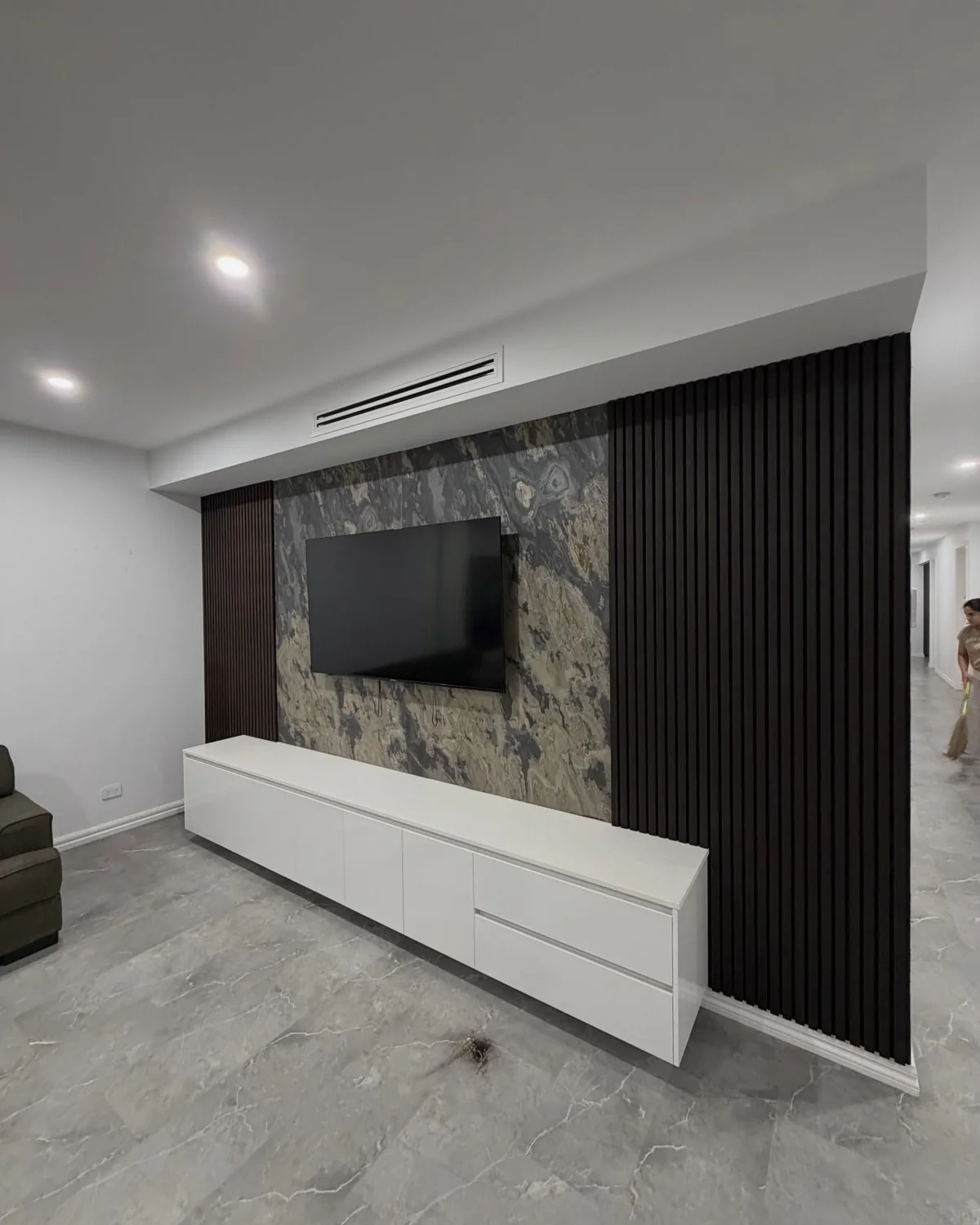 Completed modern feature wall with dark vertical battens, patterned centre panel and low white cabinetry by Takshak Built